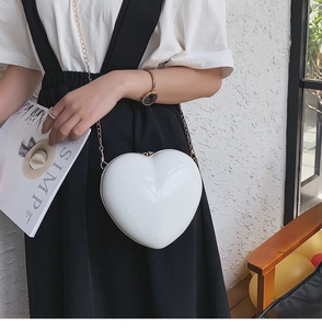 Detailansicht einer weißen herzförmigen Umhängetasche mit goldener Kette am Model