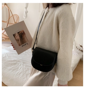 Model trägt eine schwarze Satteltasche mit verstellbarem Gurt in Wohnzimmer-Atmosphäre