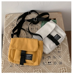 Close-up of yellow and beige canvas messenger bags with buckle straps on a vintage table