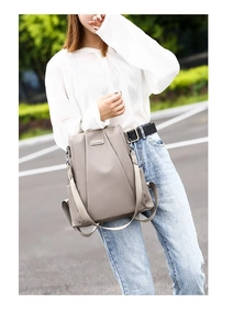 Detail of light khaki nylon backpack featuring elegant pleated front and side pocket