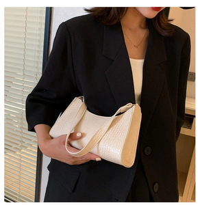 Detail of white croc-embossed PU leather shoulder bag on model with black blazer