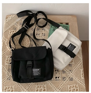 Detail of canvas messenger bag with flap buckle closure and fashion label on tabletop