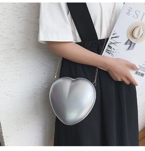 Detailansicht der silbernen herzförmigen Umhängetasche mit goldener Kette am Model