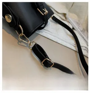 Detail of reinforced golden metal hardware and strap hooks on black leather bucket bag