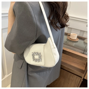 Détail d'un sac baguette en cuir verni blanc avec une boucle carrée en cristal brillant
