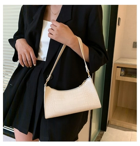 Close-up of white crocodile pattern shoulder bag with sleek gold-tone hardware detail