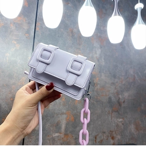 Detailopname van mini lila crossbodytas met dubbele gespen en dikke kunststof ketting