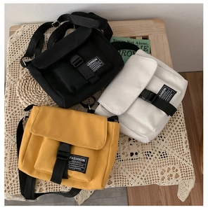 Flat lay of canvas messenger bags in black, white, and yellow on a rustic wooden table