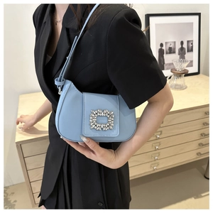 Gros plan du sac sous le bras en cuir bleu clair avec boucle carrée en strass brillants