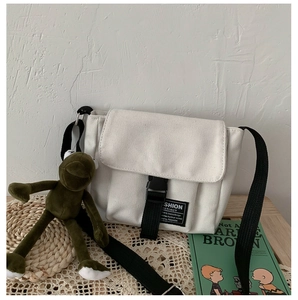 Detailed view of white canvas messenger bag with black strap and adjustable plastic buckle