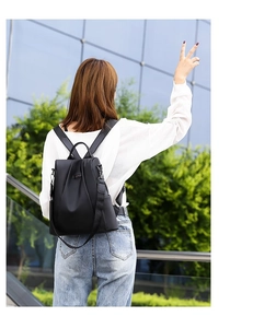 Rear view of a black waterproof nylon backpack with anti-theft zipper and leather handle