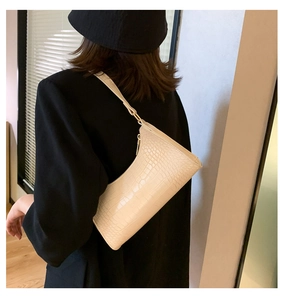 Side view of cream crocodile embossed underarm bag with zipper on model shoulder