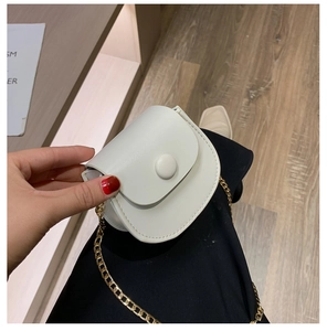 Detail van een witte mini zadeltas met gouden kettingriem en magnetische klepsluiting