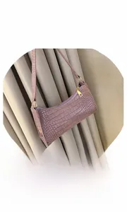 Detail of purple faux crocodile texture baguette bag with golden metal zipper closure