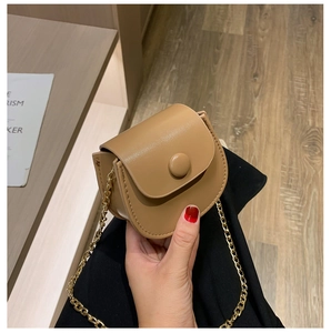 Detail van camel PU-lederen zadeltas met ronde knoopsluiting en gouden kettingband