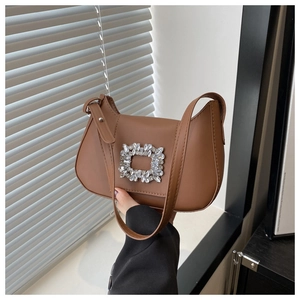 Gros plan d'un sac d'épaule en cuir caramel avec une boucle carrée en cristal argenté