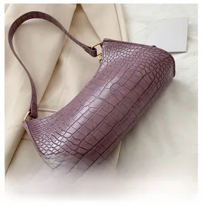 Close-up of purple crocodile pattern leather underarm bag with golden metal hardware