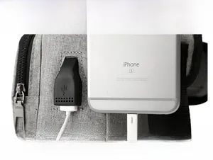 Close-up of the grey sling bag featuring an integrated USB charging port for devices
