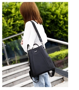 Outdoor side view of a black waterproof nylon backpack with a detachable shoulder strap