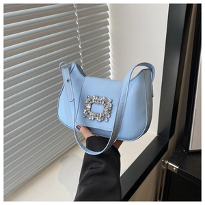 Détail d'un sac hobo bleu clair avec boucle décorative en strass carrés et bandoulière en cuir