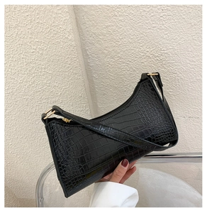 Detail of black crocodile texture leather underarm bag with elegant gold zipper hardware