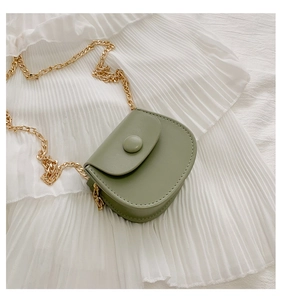 Detail van de saliegroene zadeltas van mat leer met een gouden schakelketting