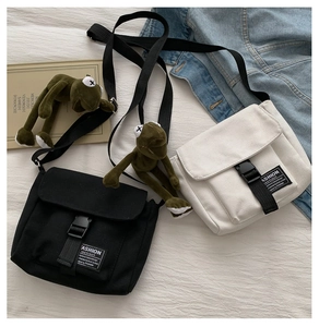 Detail of canvas messenger bags in black and white with cute plush frog charms