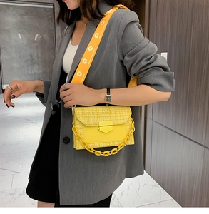 Detail of yellow patchwork crossbody bag featuring fabric texture and chain strap