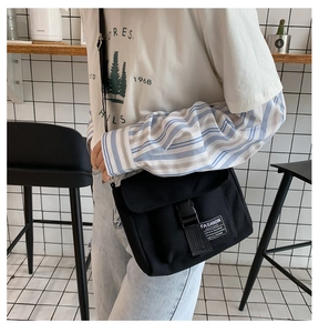 Detail of black canvas messenger bag with plastic buckle and adjustable strap