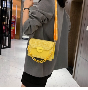 Detail view of yellow tweed crossbody bag with wide shoulder strap and gold clasp