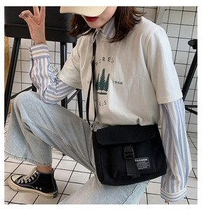 Detail of black canvas messenger bag with flap buckle closure on casual model