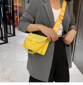 Detail of yellow tweed crossbody bag with floral strap and acrylic chain on model
