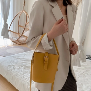 Minimalist yellow leather bucket bag with top handle and adjustable shoulder strap