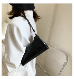 Close-up of black crocodile pattern baguette bag with glossy texture and gold buckle