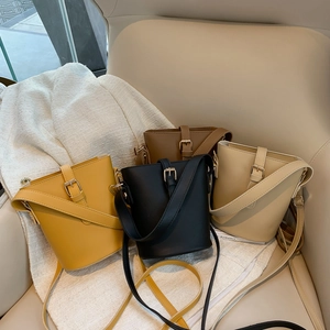 Minimalist bucket bags in yellow, black, brown, and cream white on a chair