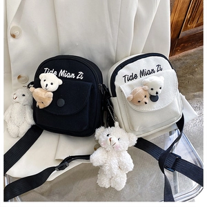 Detail of cute canvas crossbody bags featuring plush bear charms and embroidery