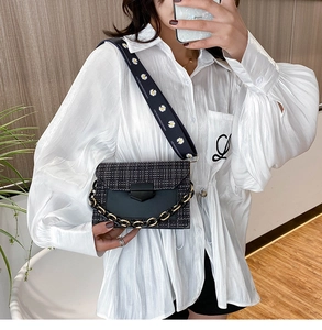 Detail of black woven crossbody bag with daisy strap and chunky gold chain