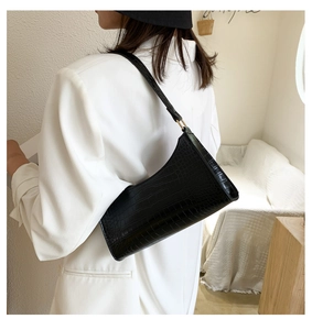 Detail of black faux crocodile skin baguette bag with elegant golden metal buckles