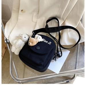 Detail of black canvas crossbody bag featuring cute bear patches and a plush sheep charm