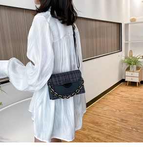 Detail of tweed crossbody bag featuring two-tone metal chain and leather patchwork
