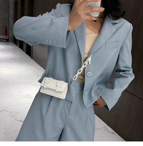 Detailopname van een witte mini vierkante crossbodytas met een dikke witte ketting