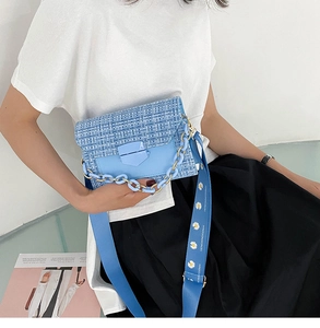 Detail of blue tweed crossbody bag featuring daisy print wide strap and chain accent