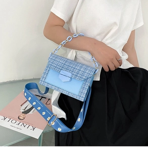 Close-up of light blue tweed crossbody bag with daisy strap and resin chain
