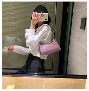 Detailed view of purple crocodile pattern baguette bag worn as a shoulder bag