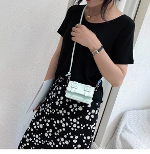 Zijaanzicht van mintgroene mini crossbodytas gedragen door model in bloemenjurk