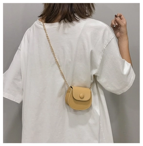 Detailopname van een mini gele zadeltas met gouden ketting op een model