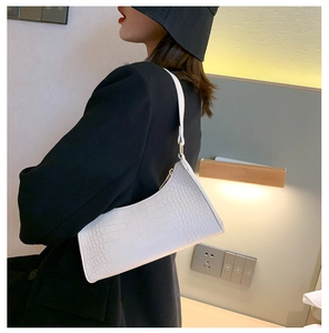 Close-up of white crocodile pattern baguette bag with slim strap on model shoulder