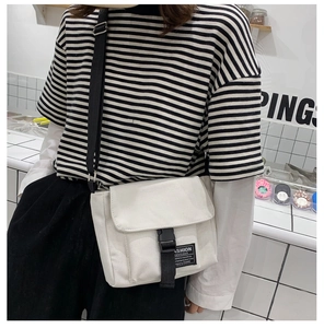 Detailed shot of white canvas messenger bag with adjustable strap and quick-release buckle