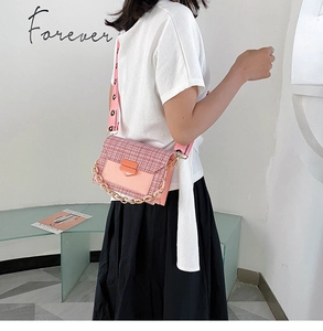 Detailed view of pink tweed shoulder bag with wide strap and chain on a model
