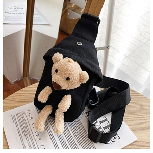 Detailed close-up of the black canvas bag featuring a 3D brown plush bear and wide strap